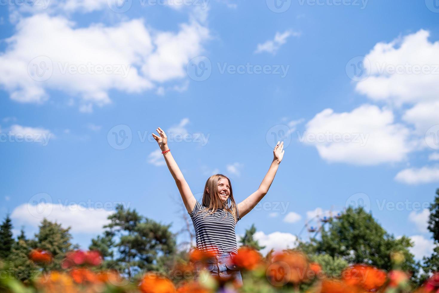 femme qui rit heureuse dans une journée ensoleillée dans la nature en été avec les mains ouvertes photo