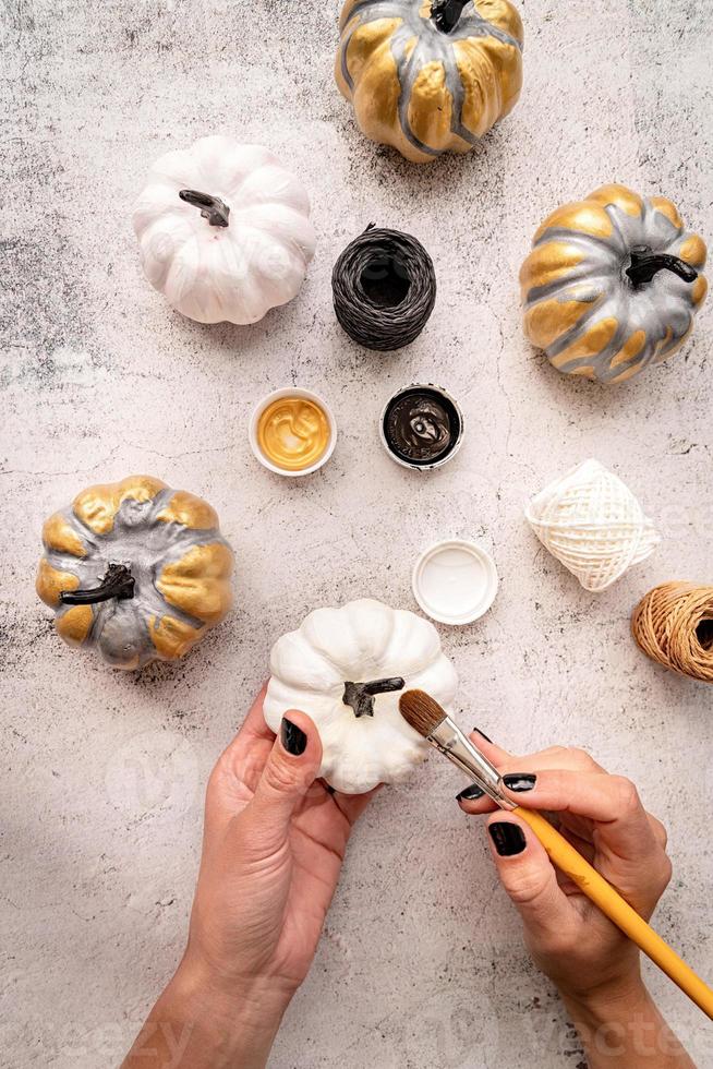 mains féminines avec des ongles noirs peignant des citrouilles pour halloween photo