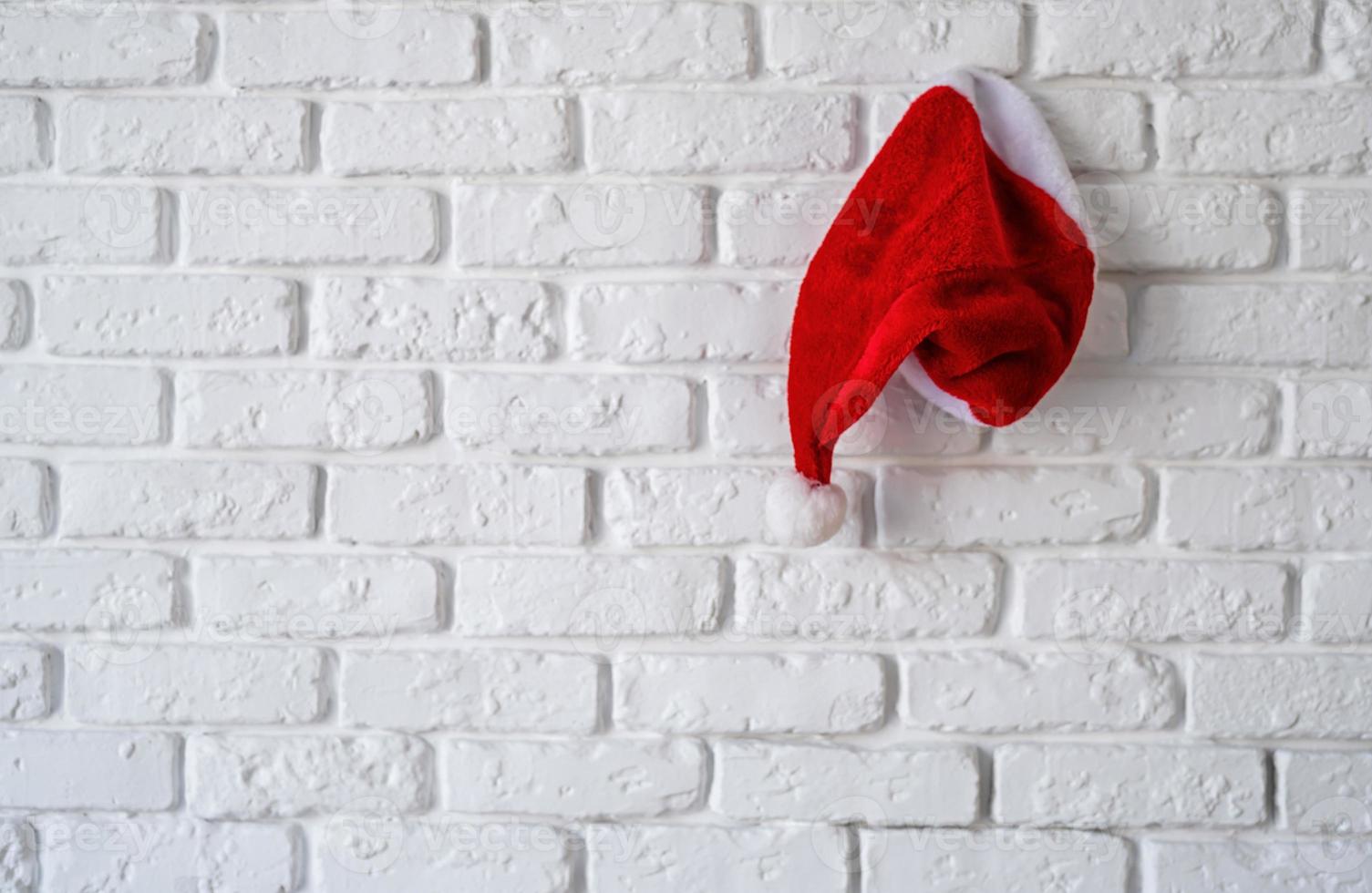 Bonnet de Noel rouge accroché au mur de briques blanches photo