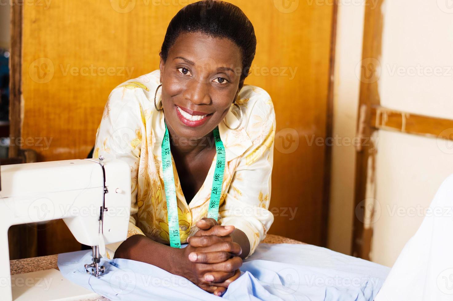 belle femme couturière souriante appuyée sur la table de sa machine à coudre. photo