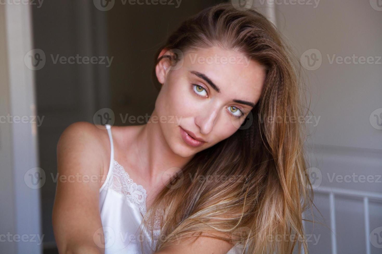 gros plan portrait de jeune femme belle sur le lit à la maison. tir de mode modèle. femme de beauté avec un sourire parfait blanc et une peau parfaite regardant la caméra à la maison, visage blanc élégant photo