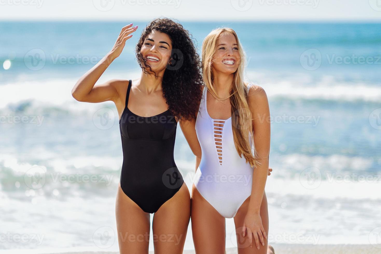 deux jeunes femmes avec de beaux corps en maillot de bain sur une plage tropicale photo