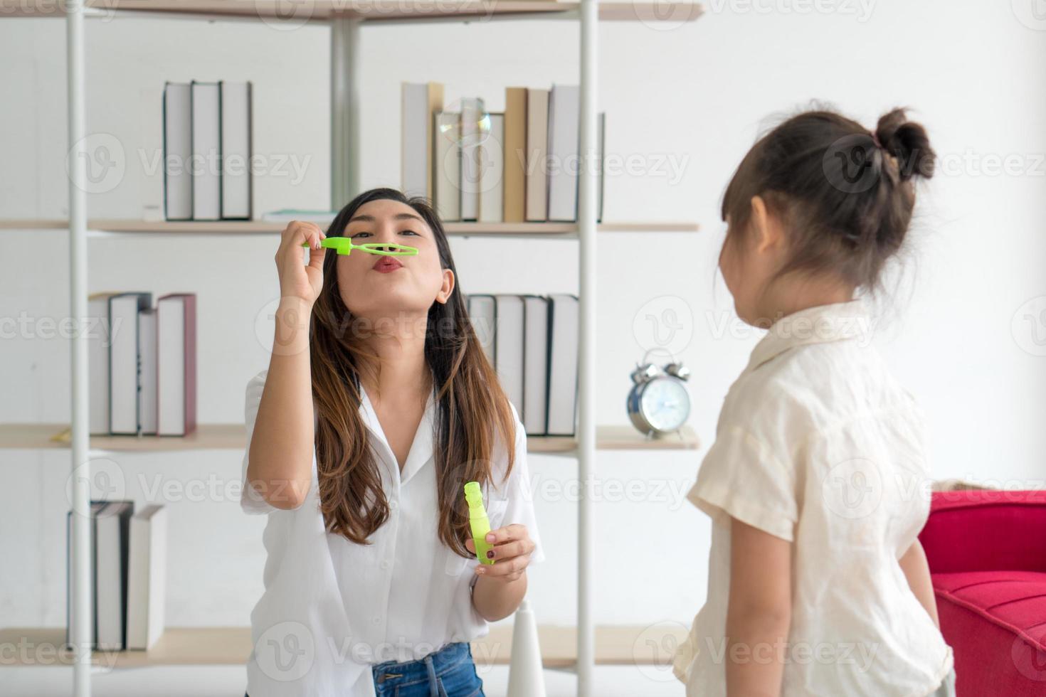 jeune mère asiatique plaing des bulles de savon avec son enfant dans le salon à la maison en été. concept de famille ensemble photo