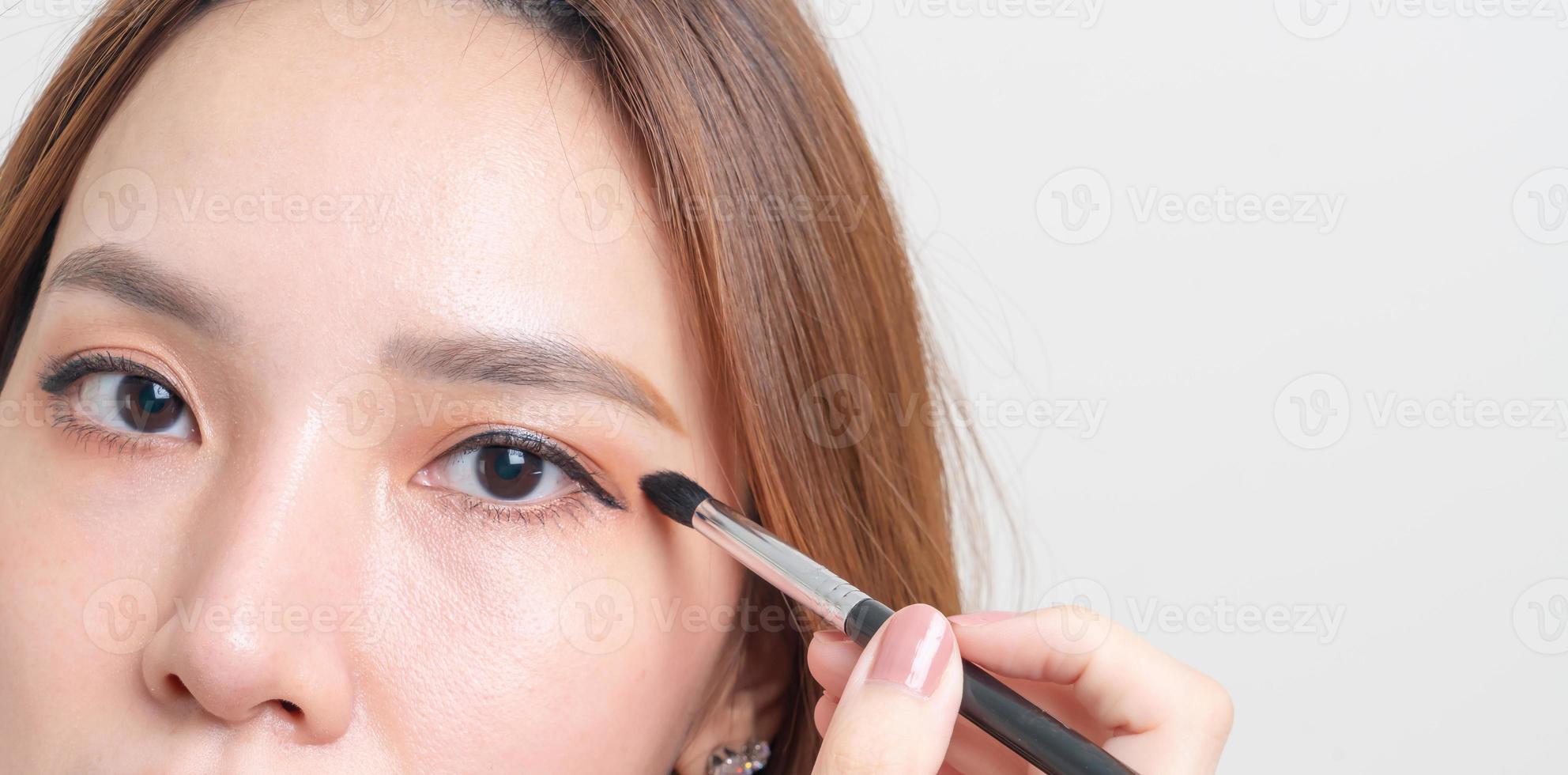 Portrait belle femme avec pinceau pour les yeux de maquillage photo