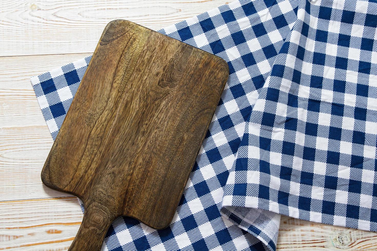 gros plan de planche à découper avec nappe à carreaux sur fond de bois. photo