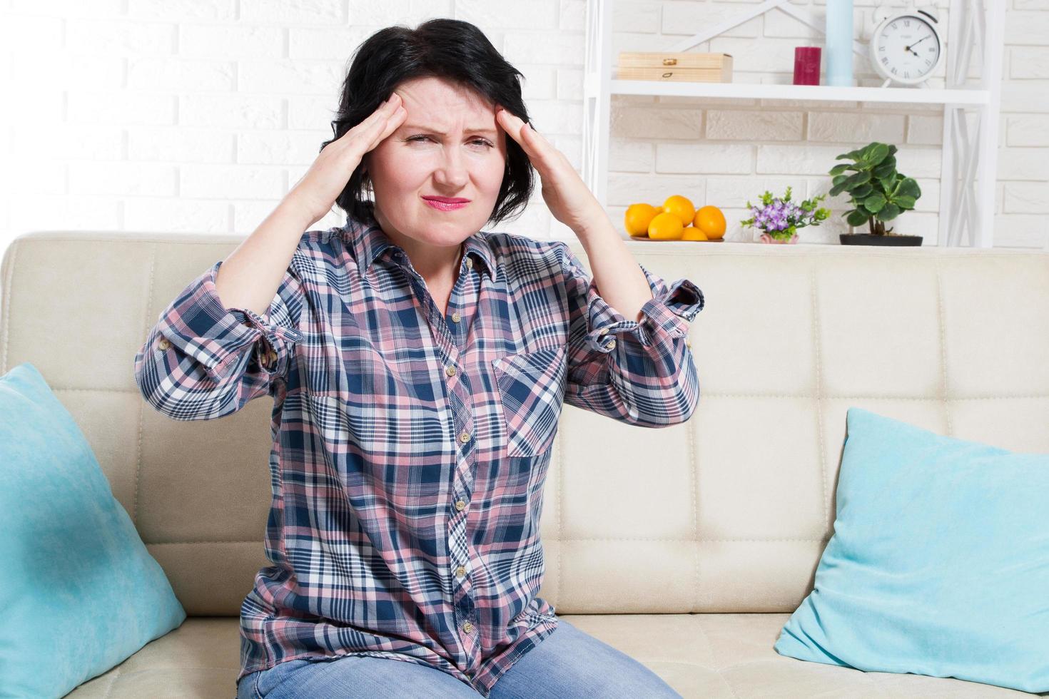 femme d'âge moyen souffrant de maux de tête et de stress tenant ses mains sur ses tempes avec les yeux ouverts de douleur photo