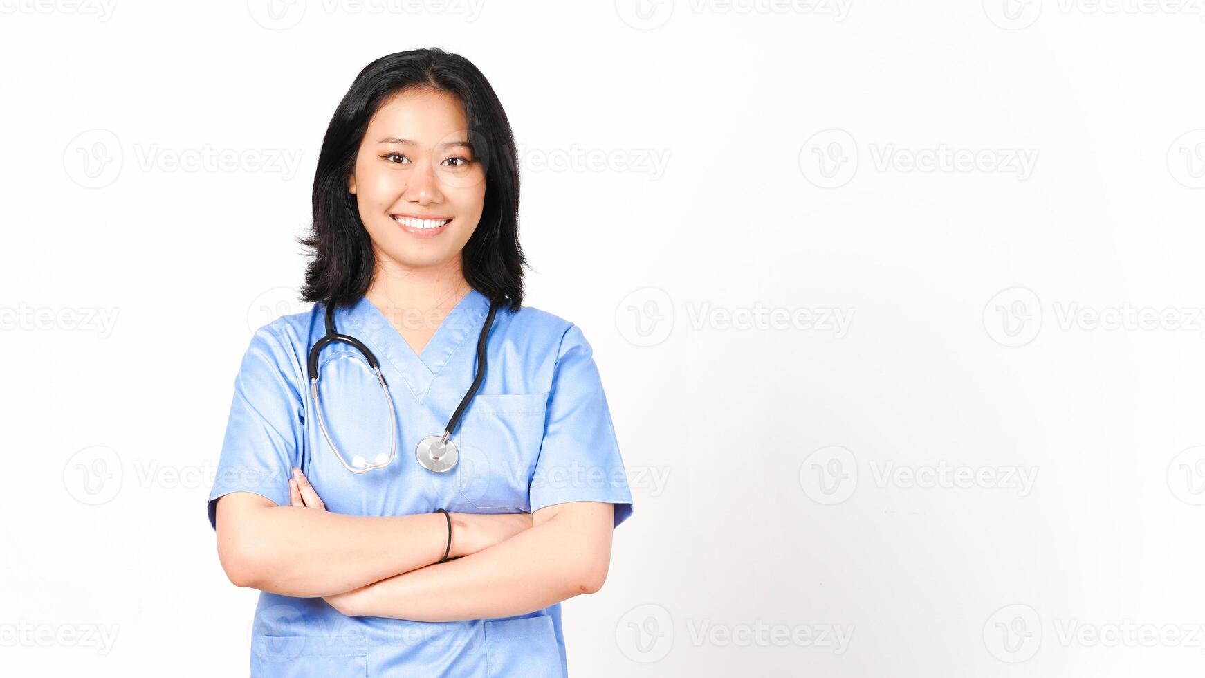 Jeune asiatique femelle médecin pliant bras souriant et à la recherche à caméra isolé sur blanc Contexte photo