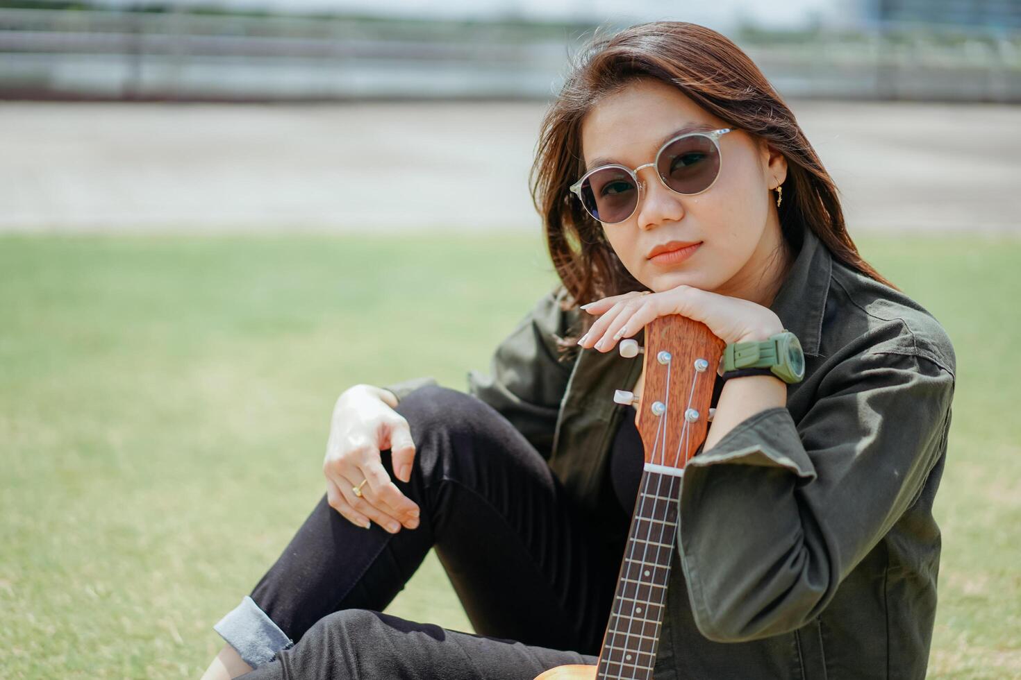 en jouant ukulélé de Jeune magnifique asiatique femme portant veste et noir jeans posant en plein air photo