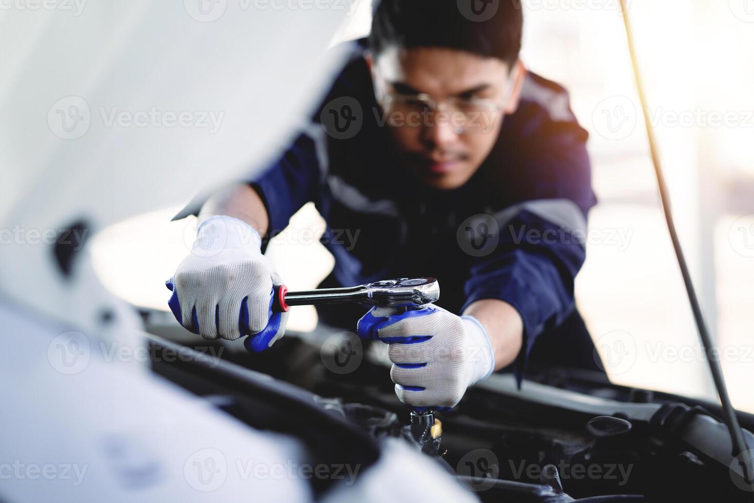 auto mécanicien est travail sur voiture moteur dans mécanicien magasin. une mécanicien dans uniforme est travail sur une voiture service. travail dans réparation magasins et entretien prestations de service. photo