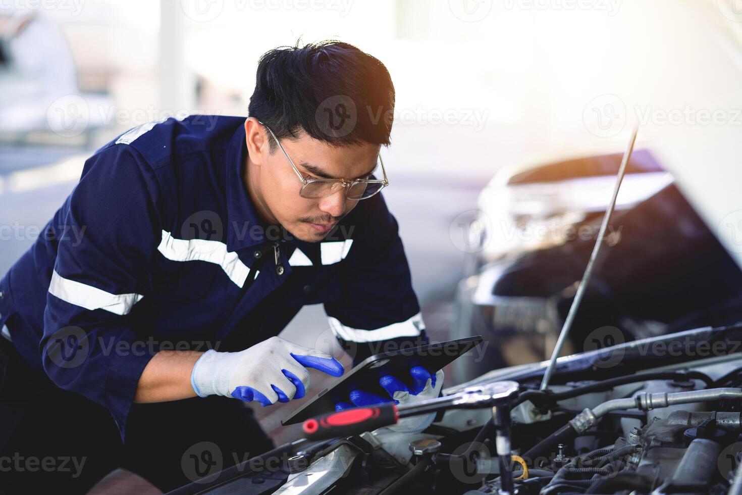auto mécanicien est travail sur voiture moteur dans mécanicien magasin. une mécanicien dans uniforme est travail sur une voiture service. travail dans réparation magasins et entretien prestations de service. photo