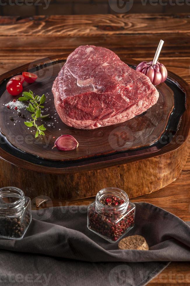 Croûte de bœuf cru picanha brésilien sur une planche à découper en résine de bois avec des épices. table en bois. photo