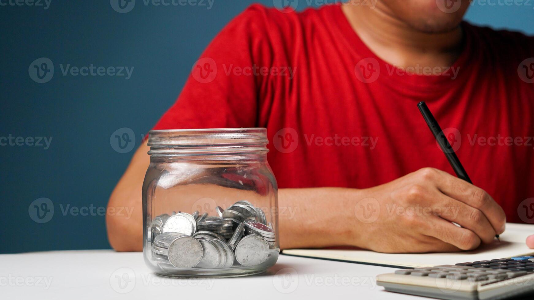 homme avec pièces de monnaie dans une clair transparent verre pot. économie argent concept photo