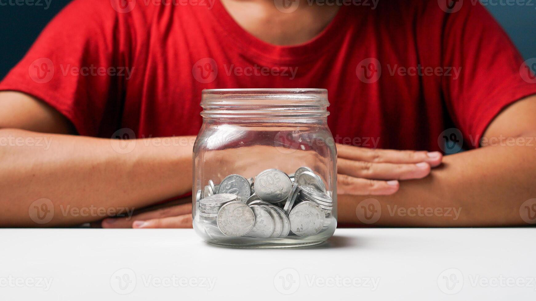 homme avec pièces de monnaie dans une clair transparent verre pot. économie argent concept photo