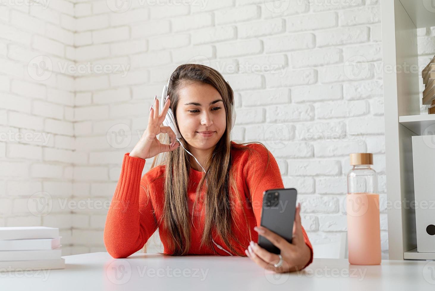 Young caucasian woman wearing écouteurs chat sur mobile montrant signe d'accord photo