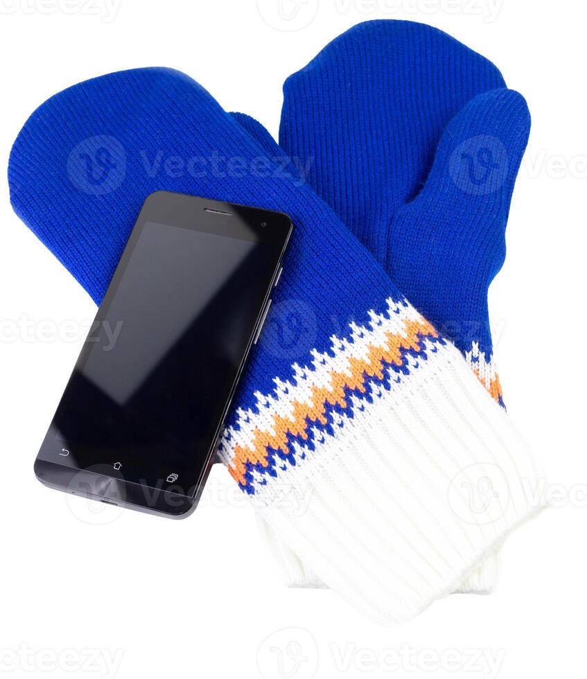 Mitaines en tricot bleu et blanc avec téléphone portable isolé sur fond blanc photo