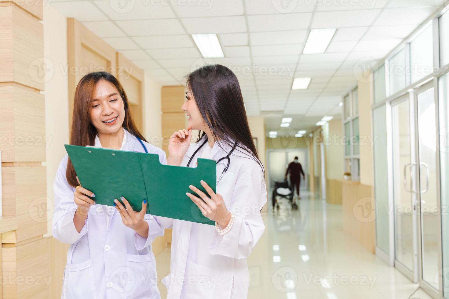 deux femmes médecins ont discuté ensemble d'un cas de patient avec un presse-papiers et se sont tenues à la réception de l'hôpital. photo