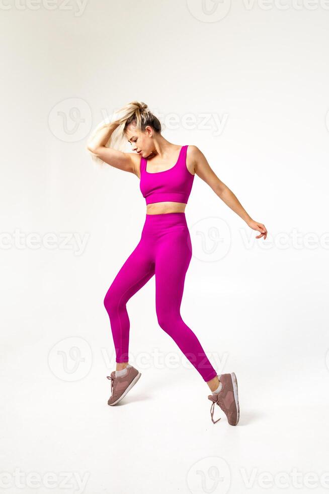 femme dans vibrant rose des sports tenue sur les orteils en portant Cheveux avec un main photo