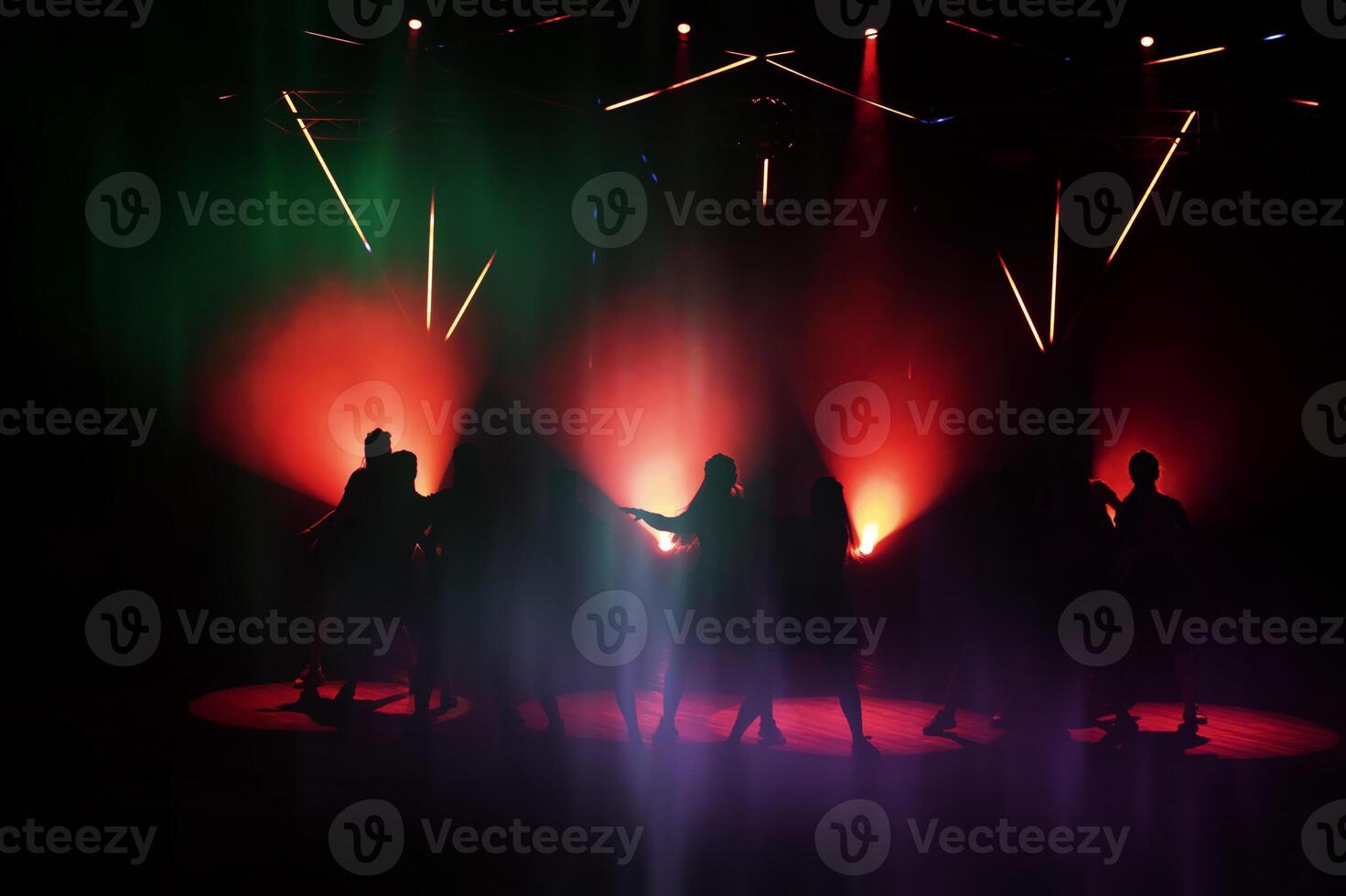 foncé silhouettes de dansant gens contre le Contexte de le lazar lumière lumières de le organiser. photo