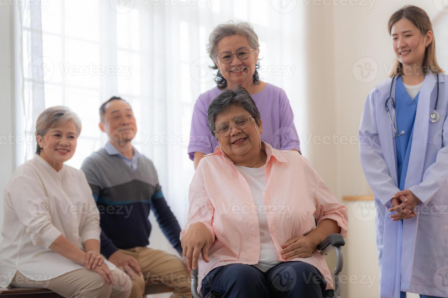 asiatique Jeune infirmière soutien couple Sénior plus âgée femme dans une fauteuil roulant. personnes âgées mature et une groupe de Sénior copains vivant dans le hôpital. socialiser de retraité personnes. photo