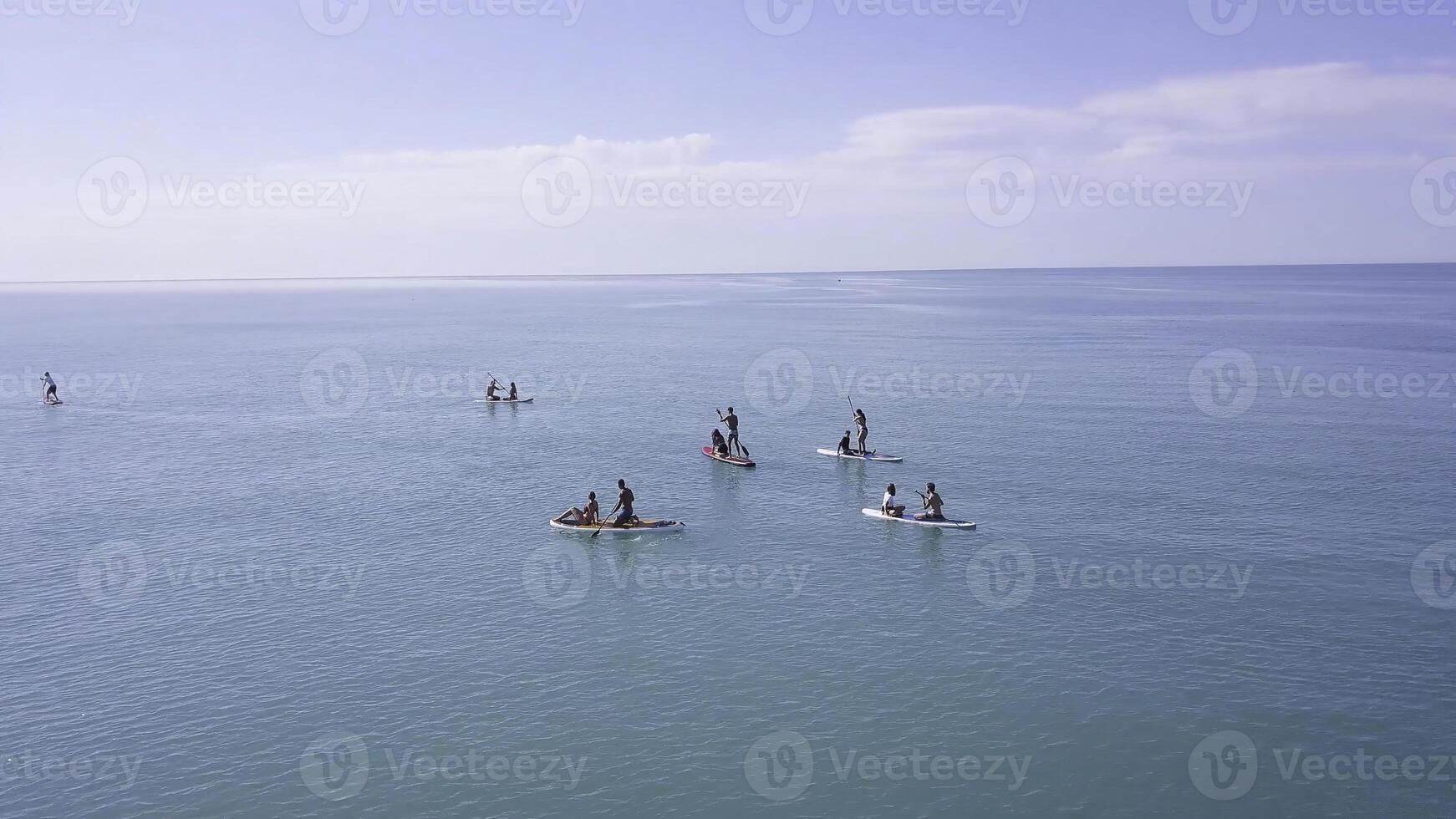 groupe de gens nager sur souper planche. agrafe. magnifique paysage marin avec gens repos sur l'eau avec souper planches. Haut vue de turquoise mer avec gens sur nager planches photo