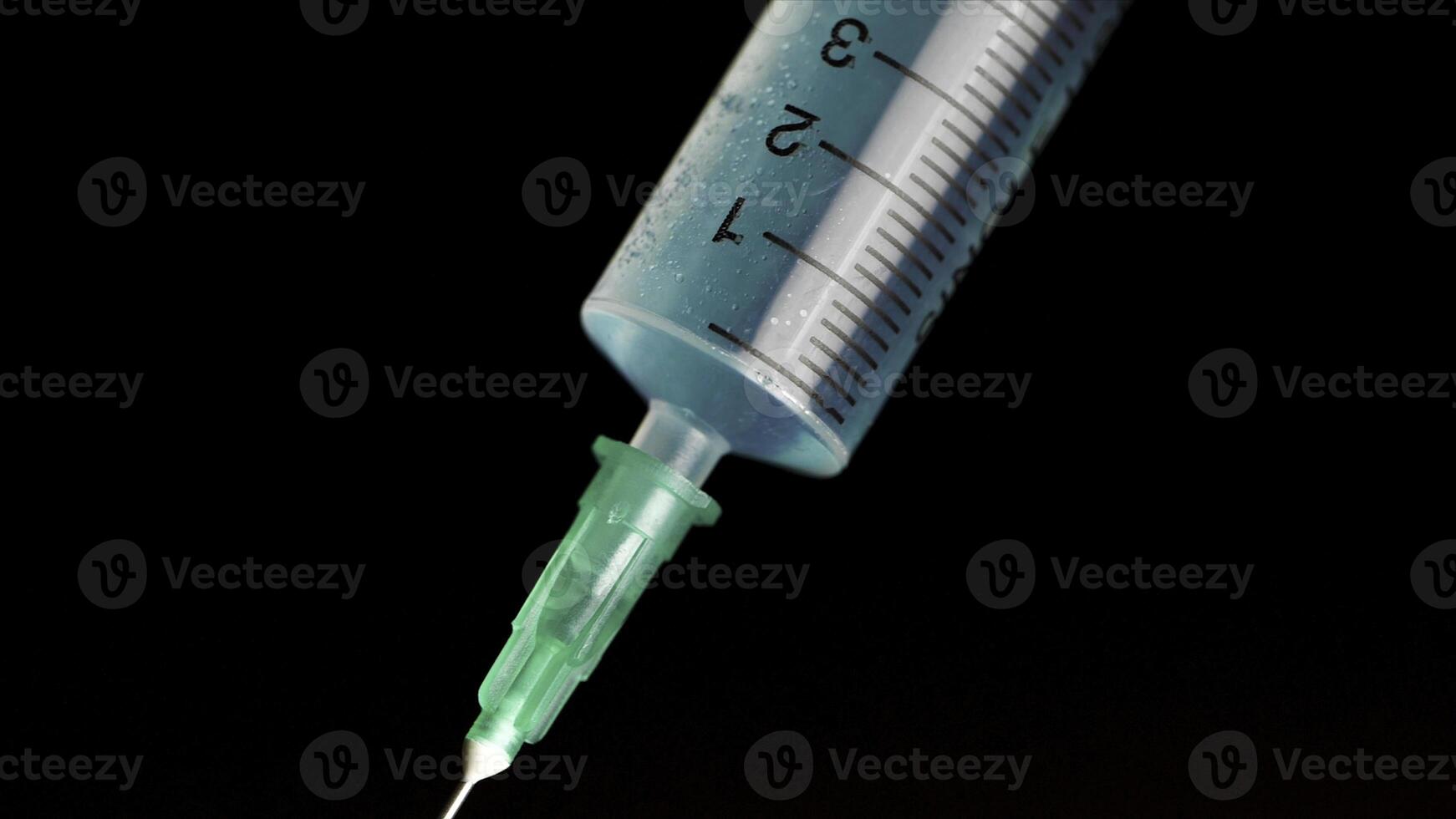 prise vaccin dans une verre seringue de une ampoule sur une noir Contexte. fermer. seringue est dactylographié dans turquoise fluide injection de maladies sérieux les maladies, le concept de médicament photo