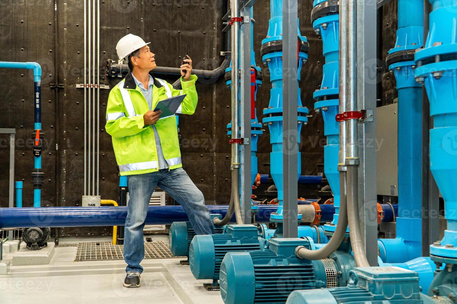 asiatique homme ouvrier dans protecteur uniforme et avec casque en utilisant tablette pour vérification Température dans tuyaux usine intérieur. photo