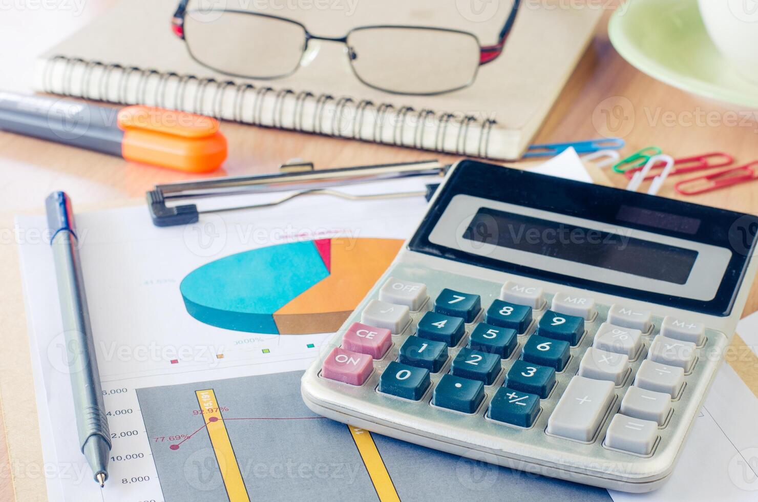 Les données graphisme calculatrice, stylo, des lunettes et une tasse de café et mettre sur votre bureau. photo