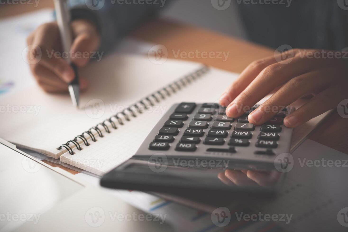 le comptable main est en utilisant le calculatrice. pour Coût une analyse profit et perte et impôt calcul concept préparation de financier déclarations photo