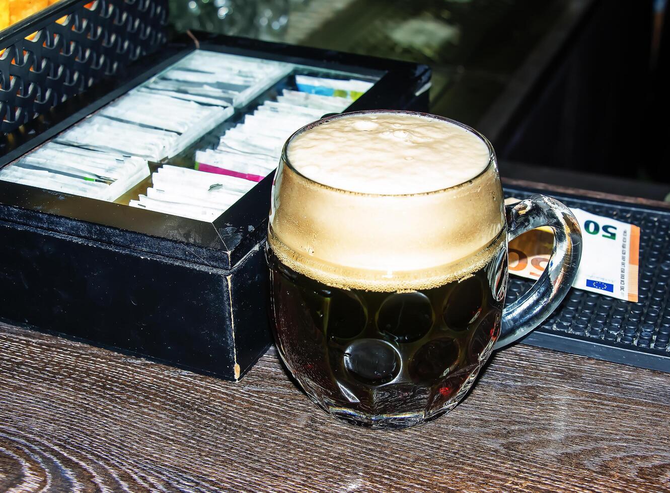 une agresser de foncé Bière moussant sur une en bois tableau. photo