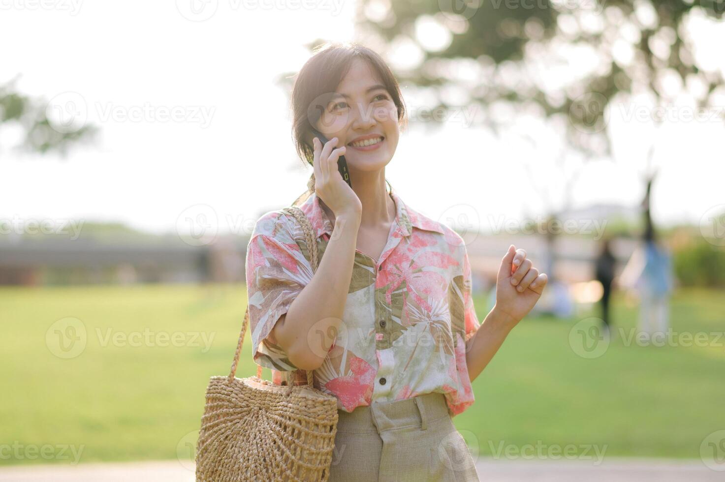 portrait de asiatique Jeune femme voyageur avec tissage panier, mobile téléphone sur vert Publique parc Contexte. périple voyage mode de vie, monde Voyage explorateur ou Asie été tourisme concept. photo