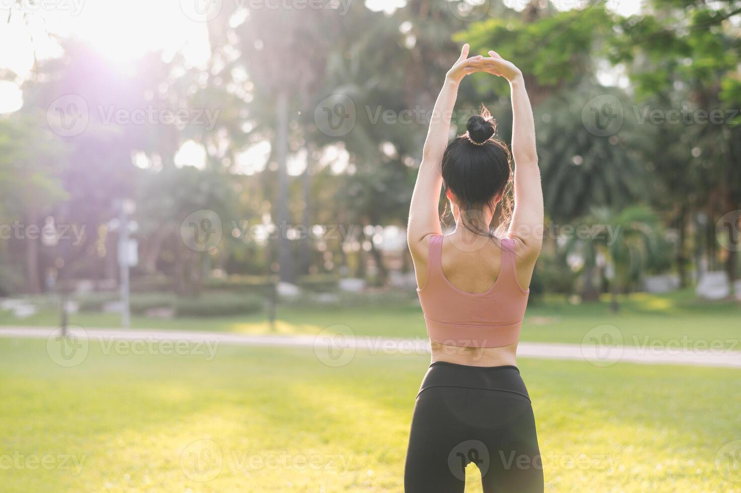 bien-être et en bonne santé mode de vie portrait 30s asiatique femme dans rose tenue de sport. en train de préparer et élongation bras muscles avant le coucher du soleil courir dans le parc. aptitude à l'extérieur et embrasse équilibré vie. photo