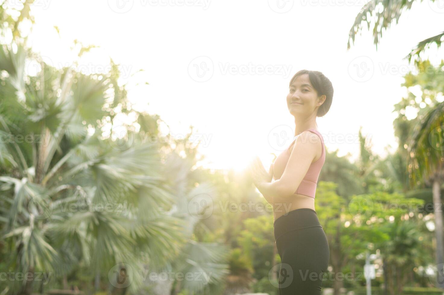 bien-être et bien étant en forme 30s Jeune asiatique femme dans rose tenue de sport engage dans yoga et s'étire sa muscles. embrasse une en bonne santé Extérieur mode de vie avec aptitude yoga fille dans une Publique parc à le coucher du soleil. photo