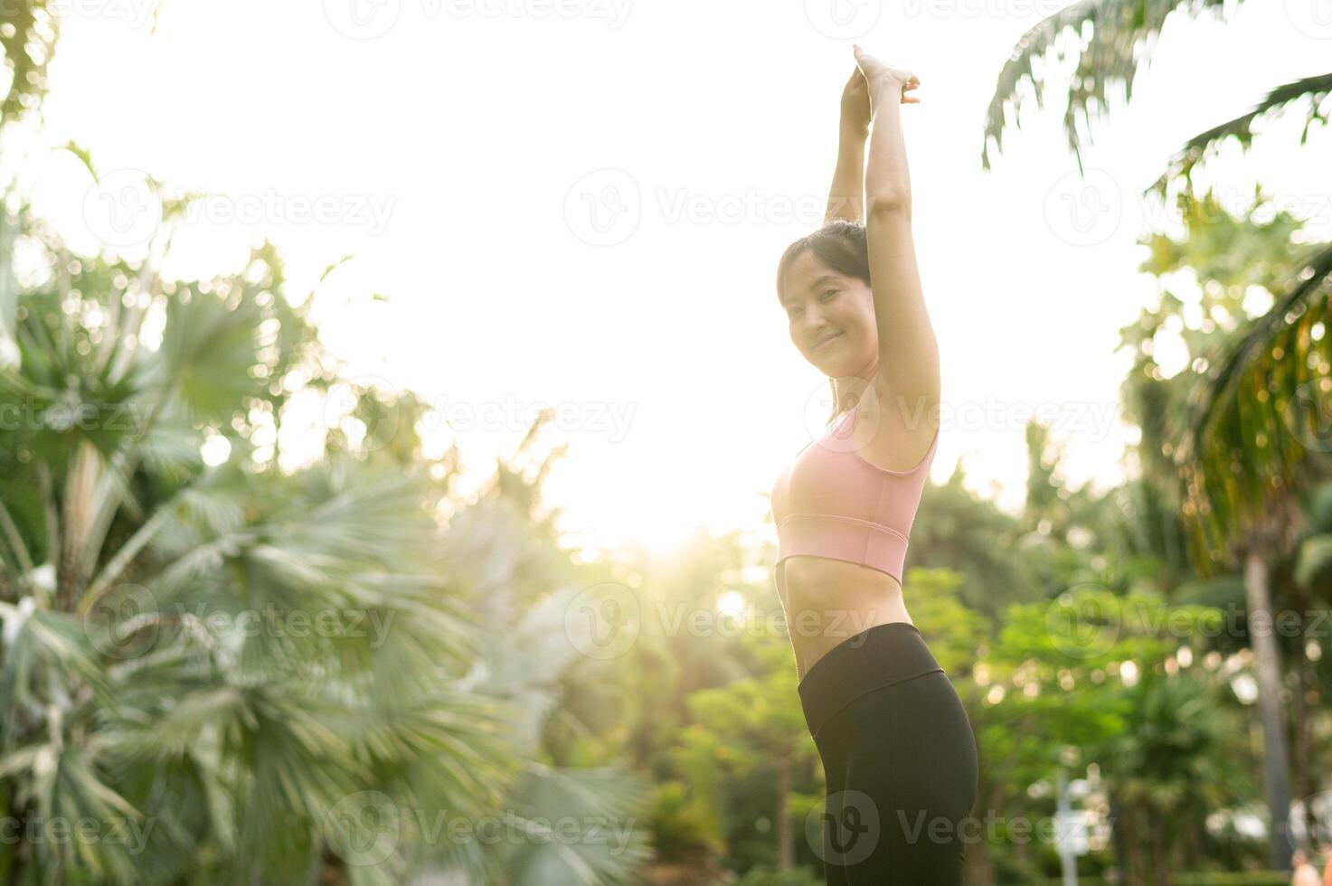 en bonne santé Extérieur mode de vie en forme 30s Jeune asiatique femme dans rose tenue de sport pièces yoga et s'étire muscles dans une Publique parc à le coucher du soleil. concept de bien-être et bien-être avec aptitude yoga fille. photo