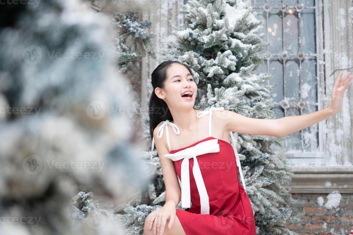 portrait de adolescent fille dans une rouge robe détendu et souriant dans une neigeux cour. photo