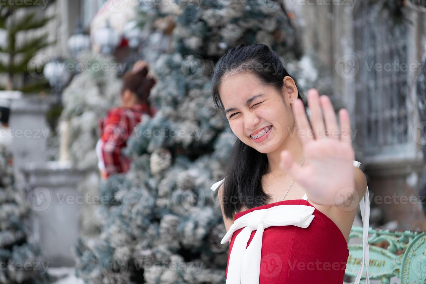 portrait de adolescent fille dans une rouge robe détendu et souriant dans une neigeux cour. photo