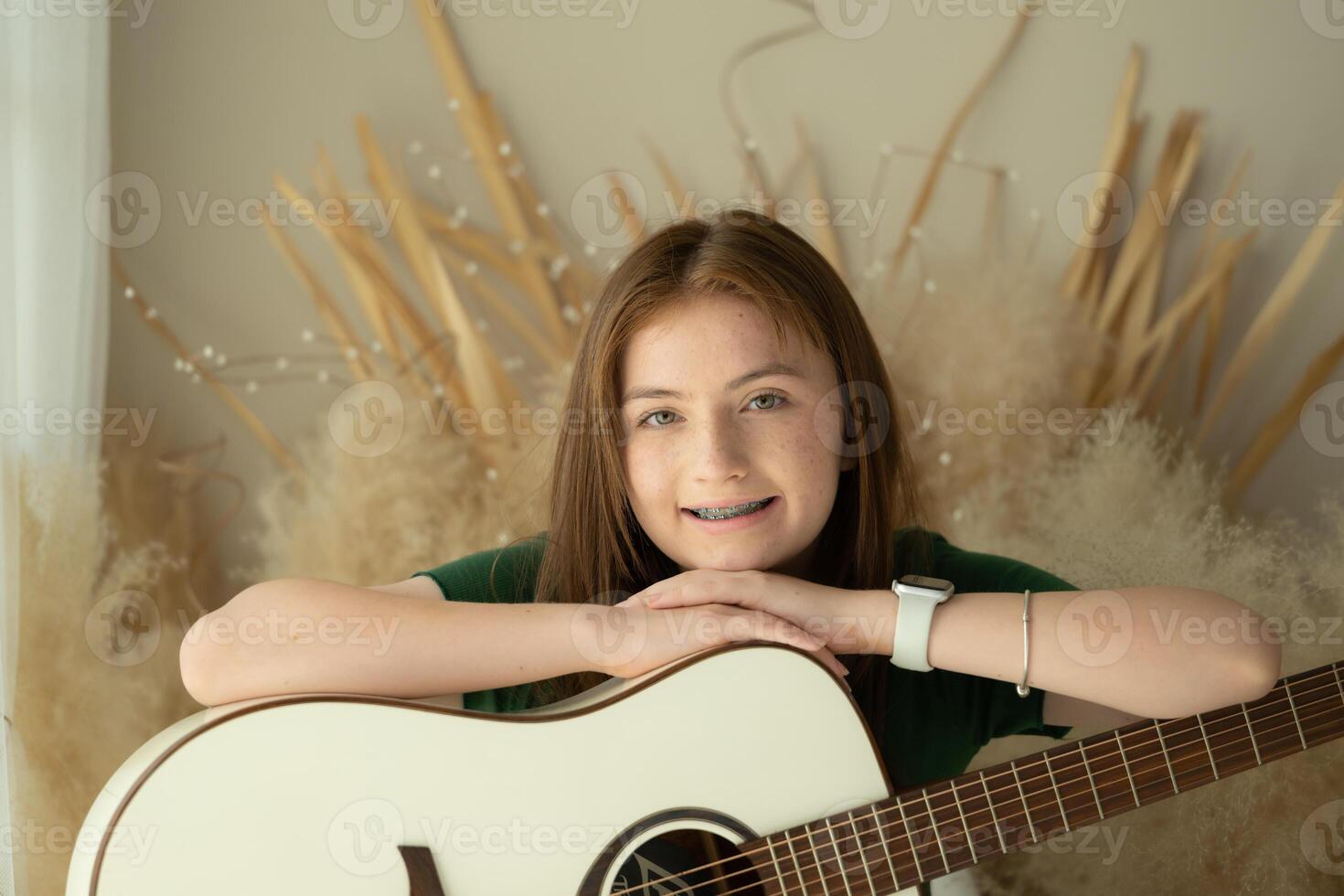 portrait de adolescent fille avec longue cheveux dans vert robe en jouant acoustique guitare. photo