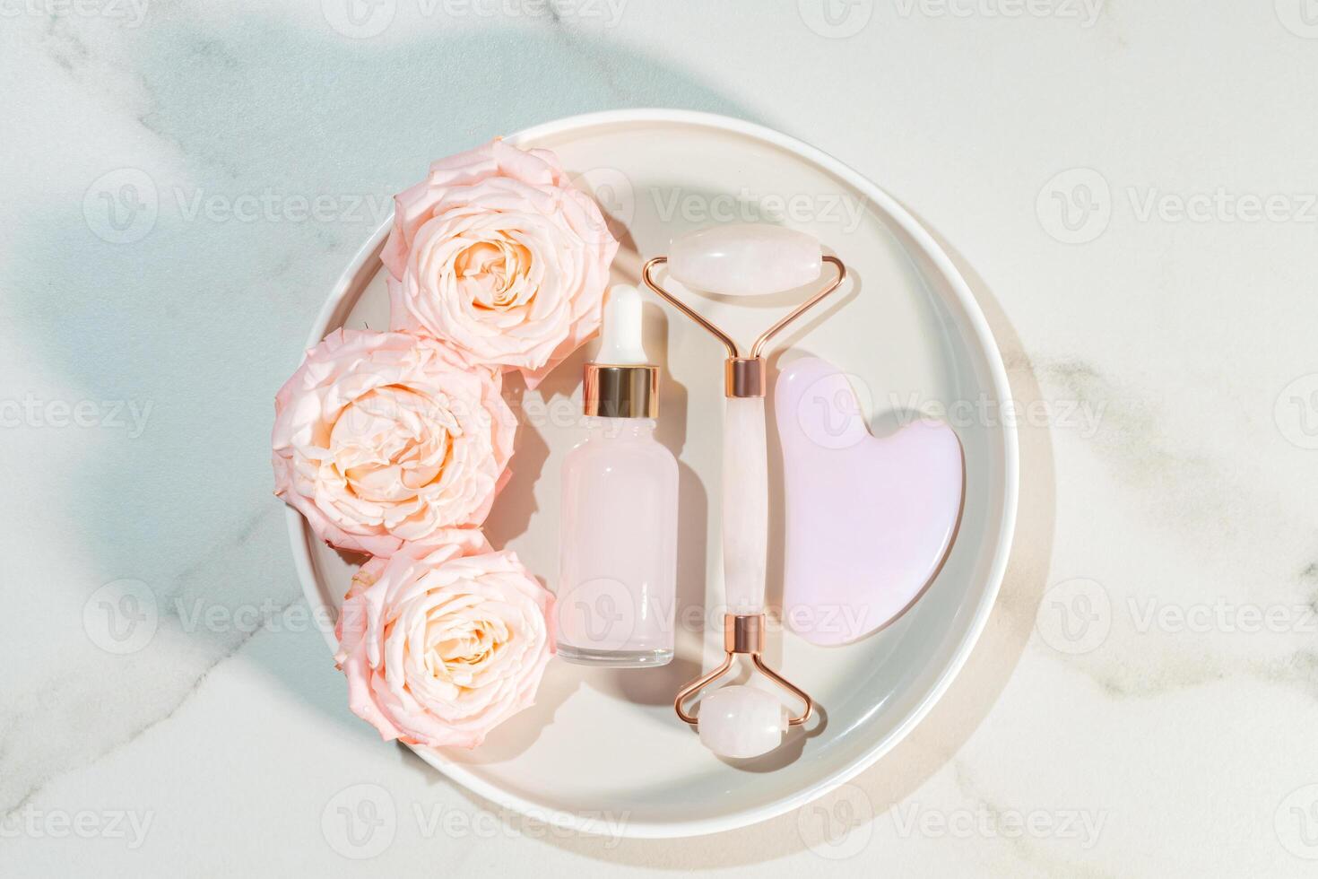 rose gua sha massage outil sur une céramique assiette sur une blanc marbre arrière-plan, Haut voir. Rose quartz jade rouleau. faciale peau se soucier à maison, anti-âge et levage thérapie. photo