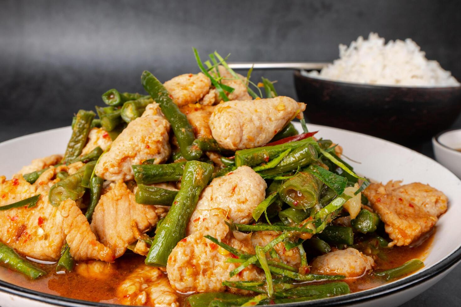 savoureux sauté porc et rouge chaud curry pâte avec asperges haricot ou longue haricot et Ingrédients sont huître sauce, poisson sauce, sucre, kaffir citron vert feuilles dans le plat manger avec cuit riz. thaïlandais cuisine photo