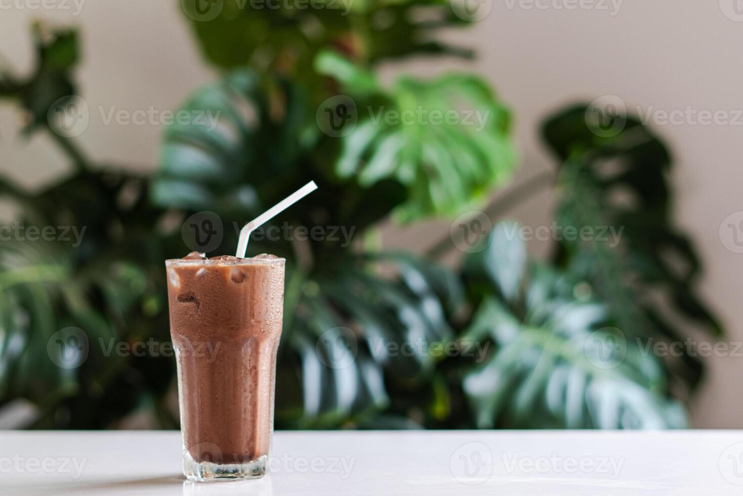 glacé cacao dans clair verre sur une blanc table avec vert feuille arrière-plan, copie espace pour votre texte photo