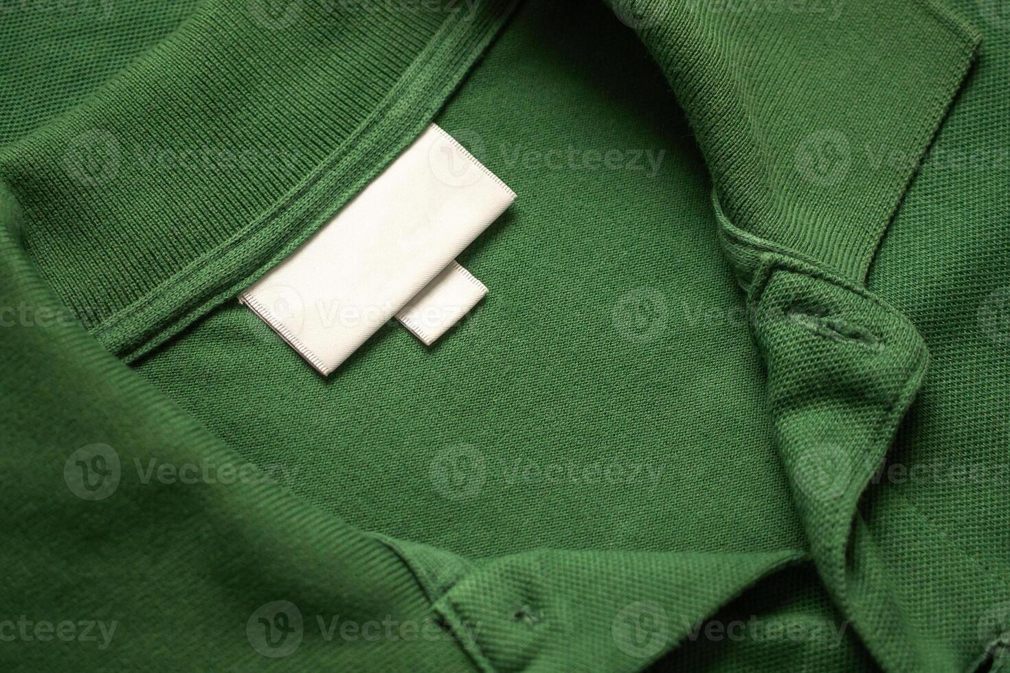 Vide blanc blanchisserie se soucier vêtements étiquette sur vert chemise en tissu texture Contexte photo