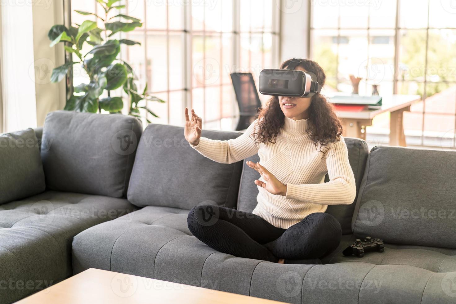 femme latine à l'aide d'un casque de réalité virtuelle sur canapé photo