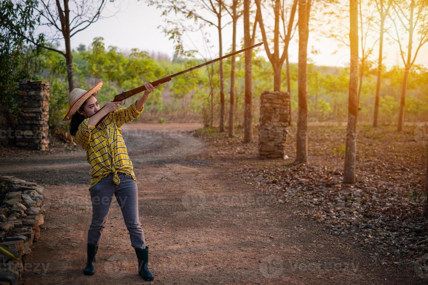 portrait de l'agriculteur femme de la mer portant un chapeau au champ de tir tiré d'un pistolet vintage à chargement par la bouche dans la ferme, jeune fille debout dans l'attitude de viser et de regarder à travers le fusil de visée photo