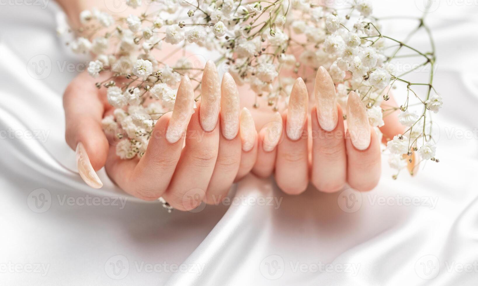 femelle mains sur une blanc soie Contexte avec magnifique perle manucure photo