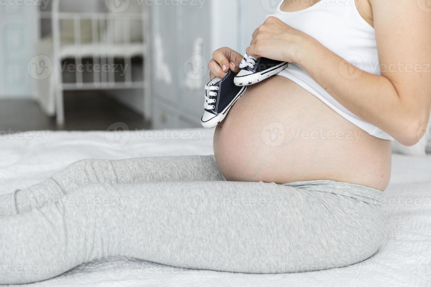 femme enceinte de côté jouant de petites chaussures photo