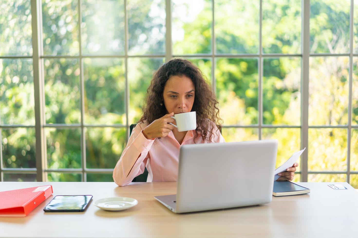 femme latine travaillant avec une tasse de café sur l'espace de travail photo
