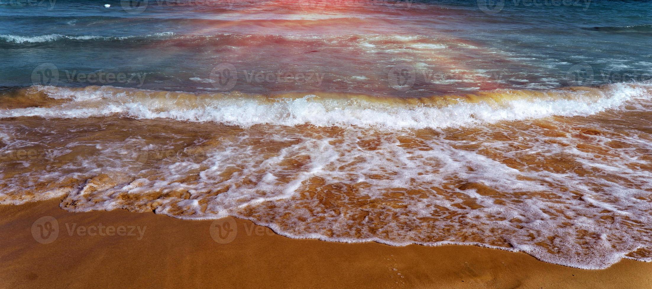 le clapotis des vagues sur la plage de sable. petites vagues de la mer aux eaux cristallines sur la plage de sable. photo