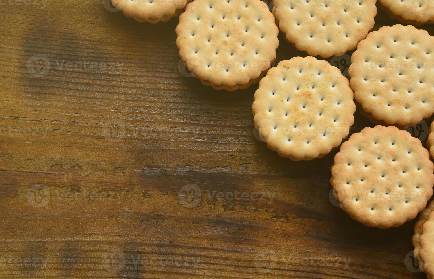 un biscuit sandwich rond fourré à la noix de coco se trouve en grande quantité sur une surface en bois marron. photo de friandises comestibles sur un fond en bois avec espace de copie