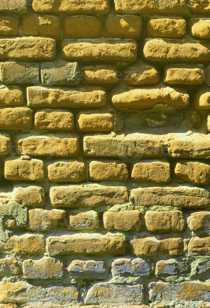 texture de mur vertical de plusieurs rangées de maçonnerie très ancienne en brique rouge. mur de briques brisé et endommagé avec des coins pincés photo