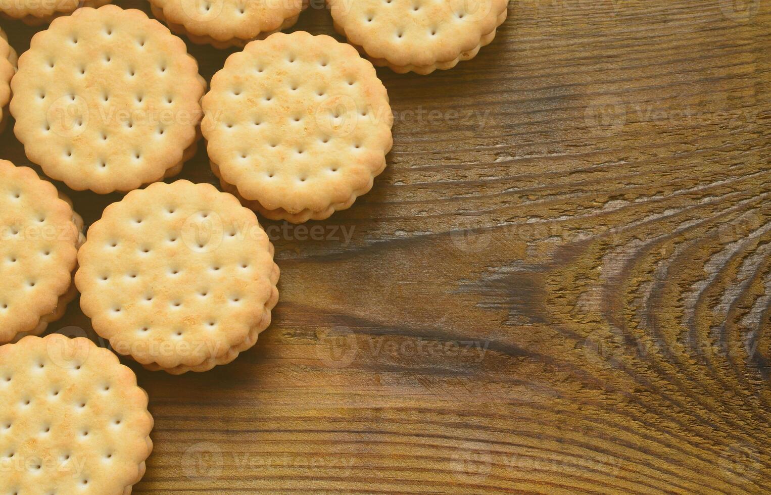 un biscuit sandwich rond fourré à la noix de coco se trouve en grande quantité sur une surface en bois marron. photo de friandises comestibles sur un fond en bois avec espace de copie