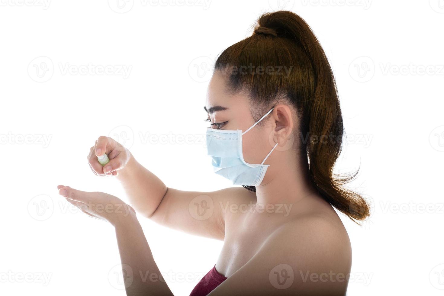 jeune femme asiatique mettant un masque médical n95 avec la main qui applique un spray d'alcool à partir de la bouteille en plastique ou des antibactériens pour empêcher la propagation des germes sur fond blanc photo